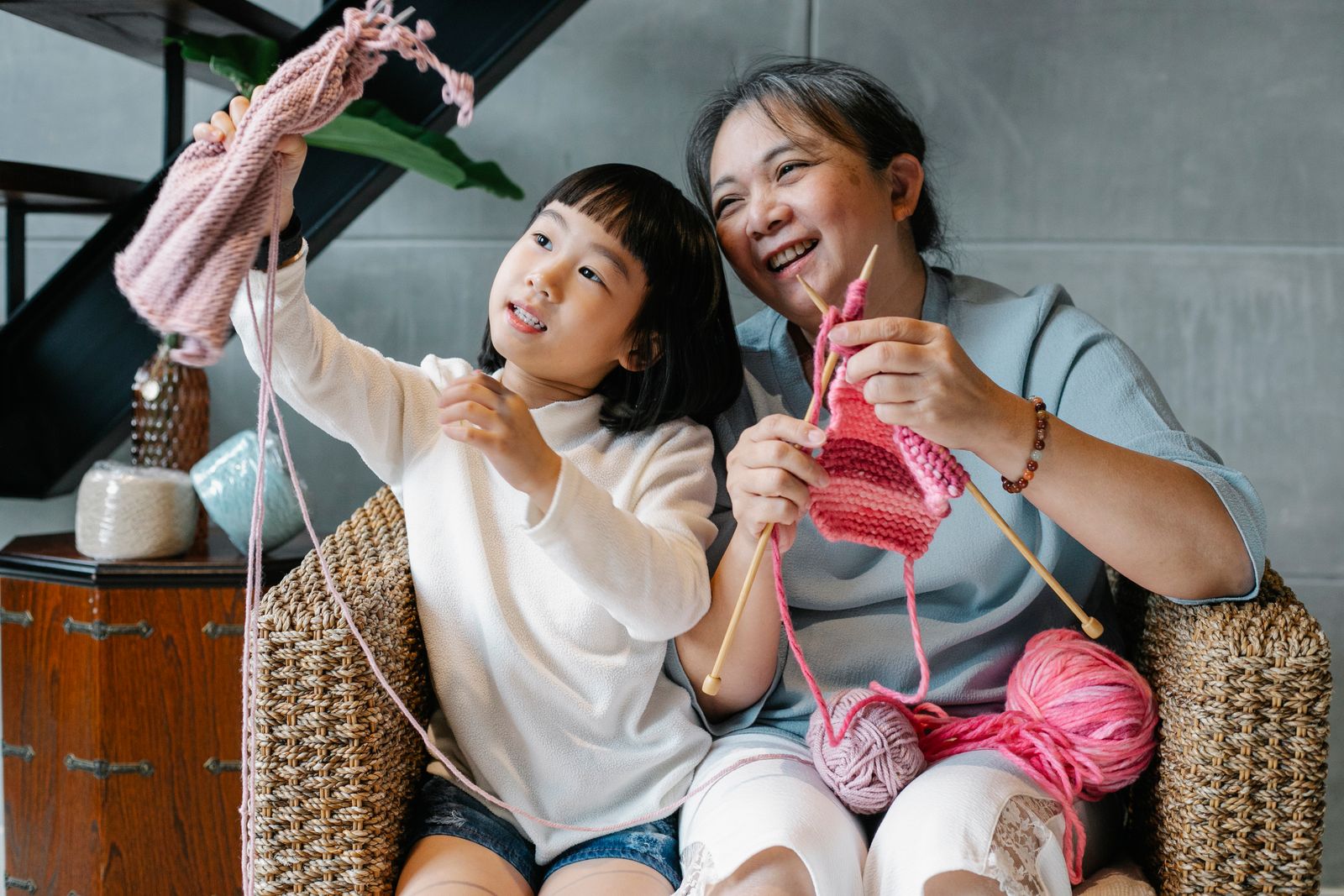 A grandmother and her granddaughter laughing together over their knitting