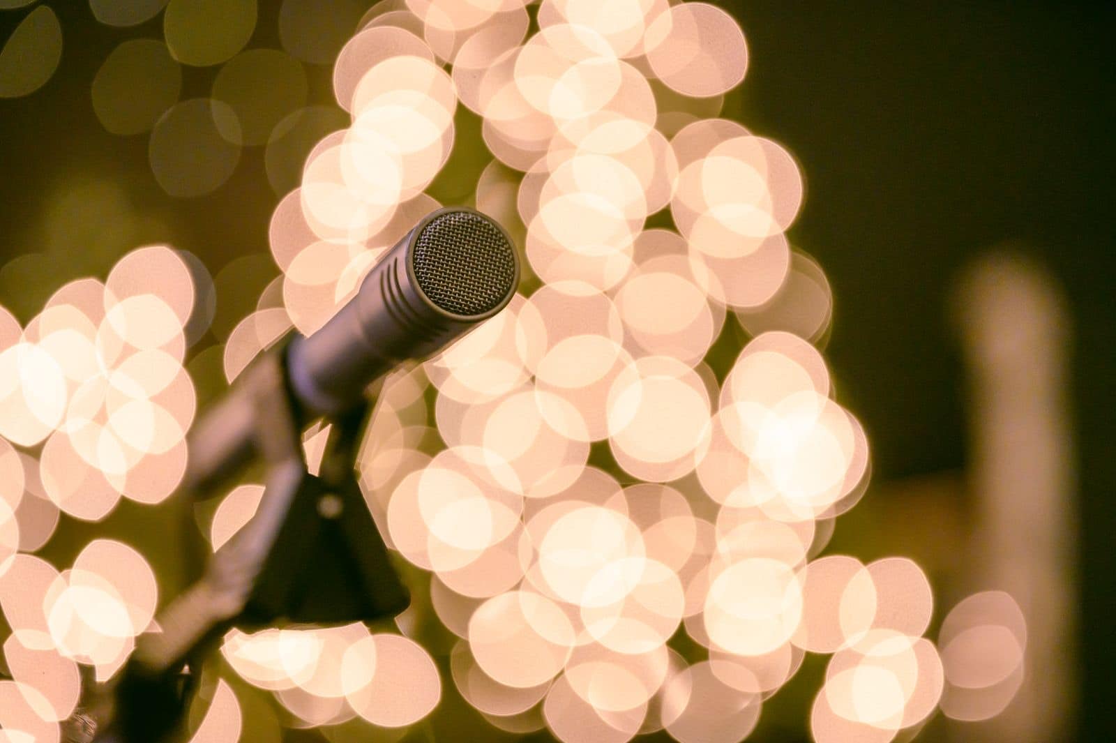 Ein Mikrofon auf einem Ständer vor warm leuchtenden Bokeh-Lichtern