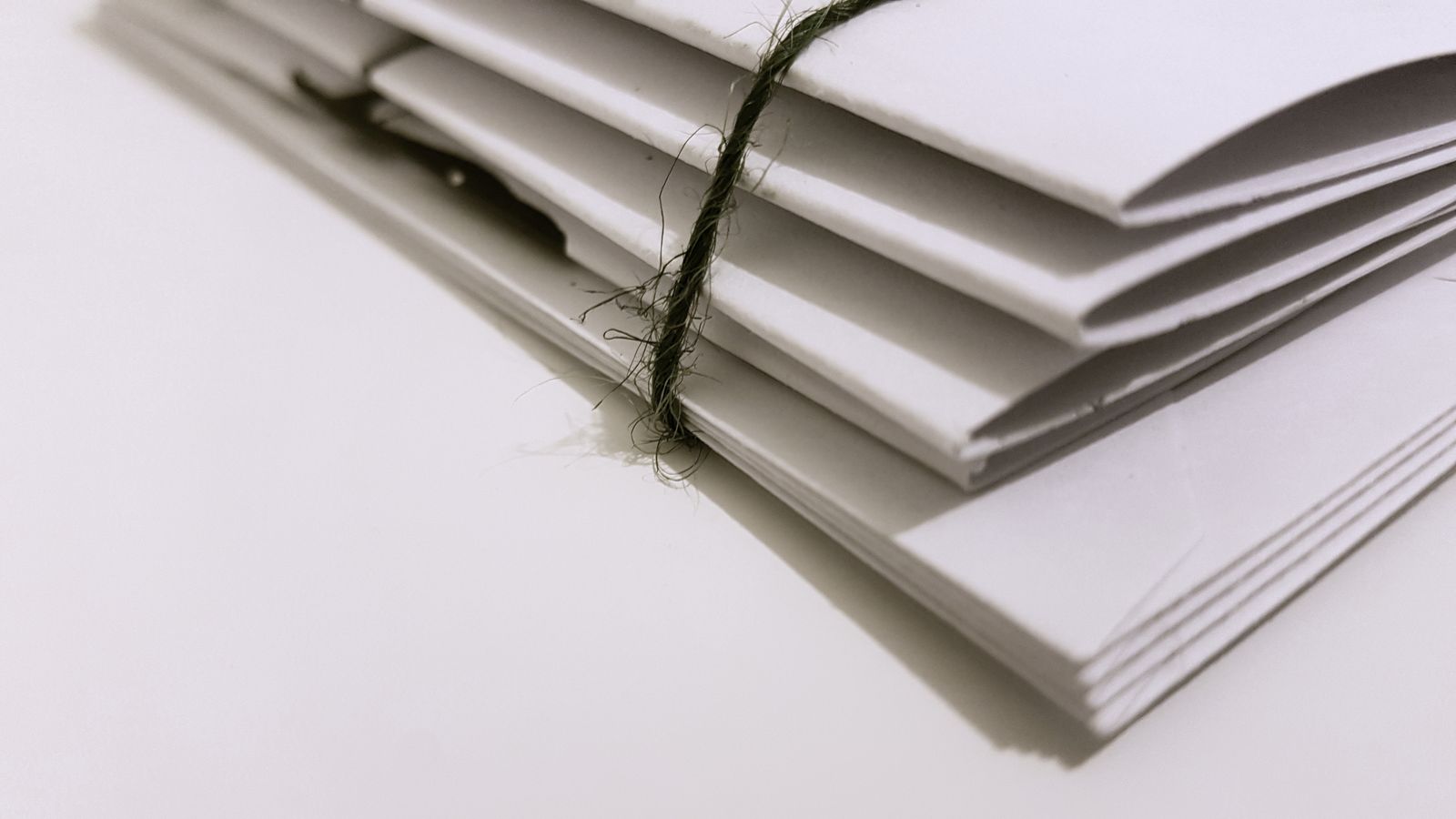 A small stack of white envelopes tied together with a length of green string