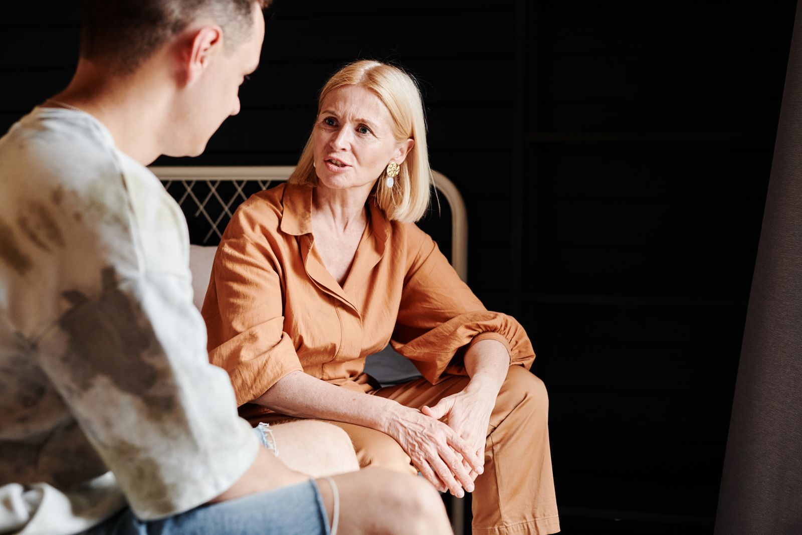 Una madre y su hijo adulto sentados juntos en casa, en mitad de una conversación