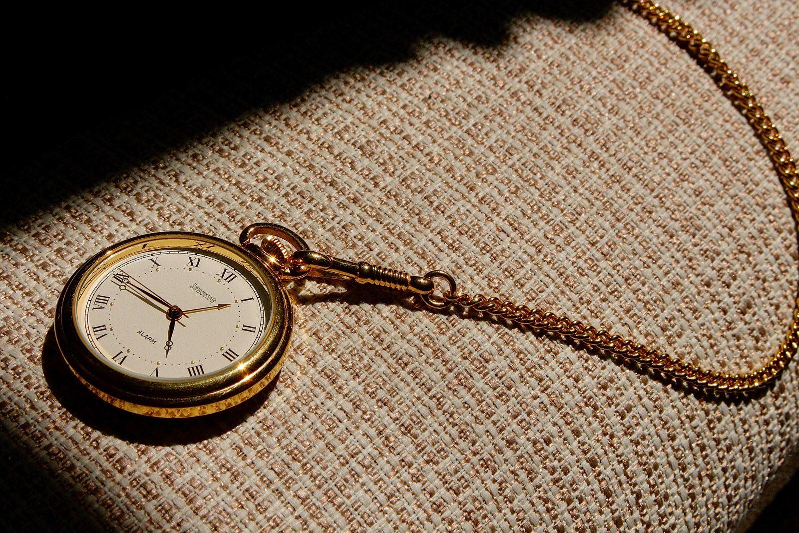 Eine goldene Taschenuhr auf gewebtem Stoff in warmem Sonnenlicht